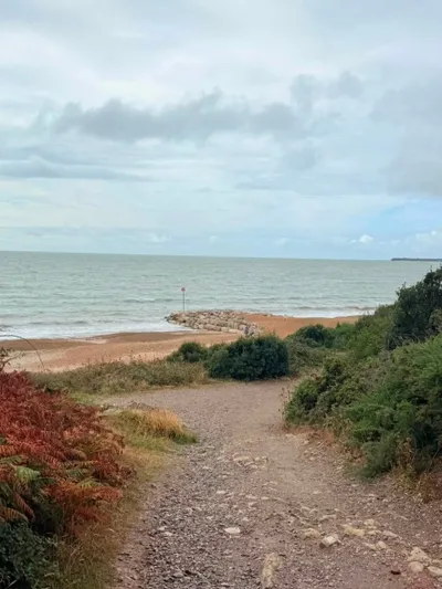 Sloped path cutting through the vegetated cliff down to Highcliffe Beach and the rock groynes