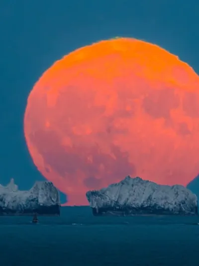 Chalk stacks of The Needles silhouetted beneath a full moon viewed from Highcliffe cliffs