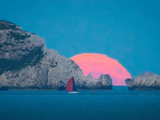 Full strawberry moon glowing above the horizon over the sea